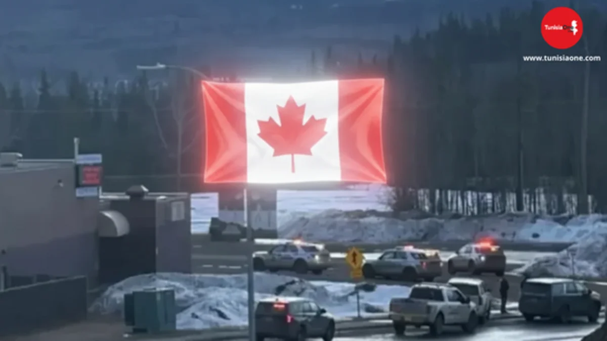 Canada Tragedy: 10 Dead in Deadly Shooting Spree in British Columbia مشهد لموقع حادث إطلاق النار في كندا مع دمج فني لعلم كندا على شكل قوس مضيء فوق سيارات الشرطة في تومبلر ريد