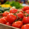 Les tomates sont-elles sûres en Tunisie ? 5 faits scientifiques sur les risques d'irrigation par les eaux usées Tomates fraîches rouge vif dans une caisse en bois, marché tunisien de légumes, pour la sécurité alimentaire 2026.